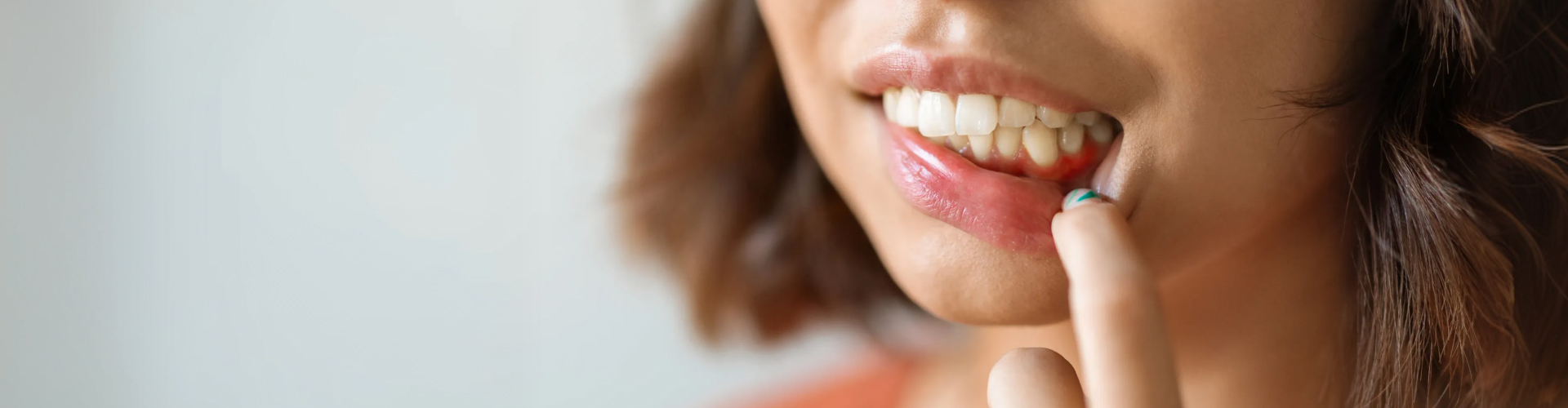 Woman pulling down lower lip to show gums.